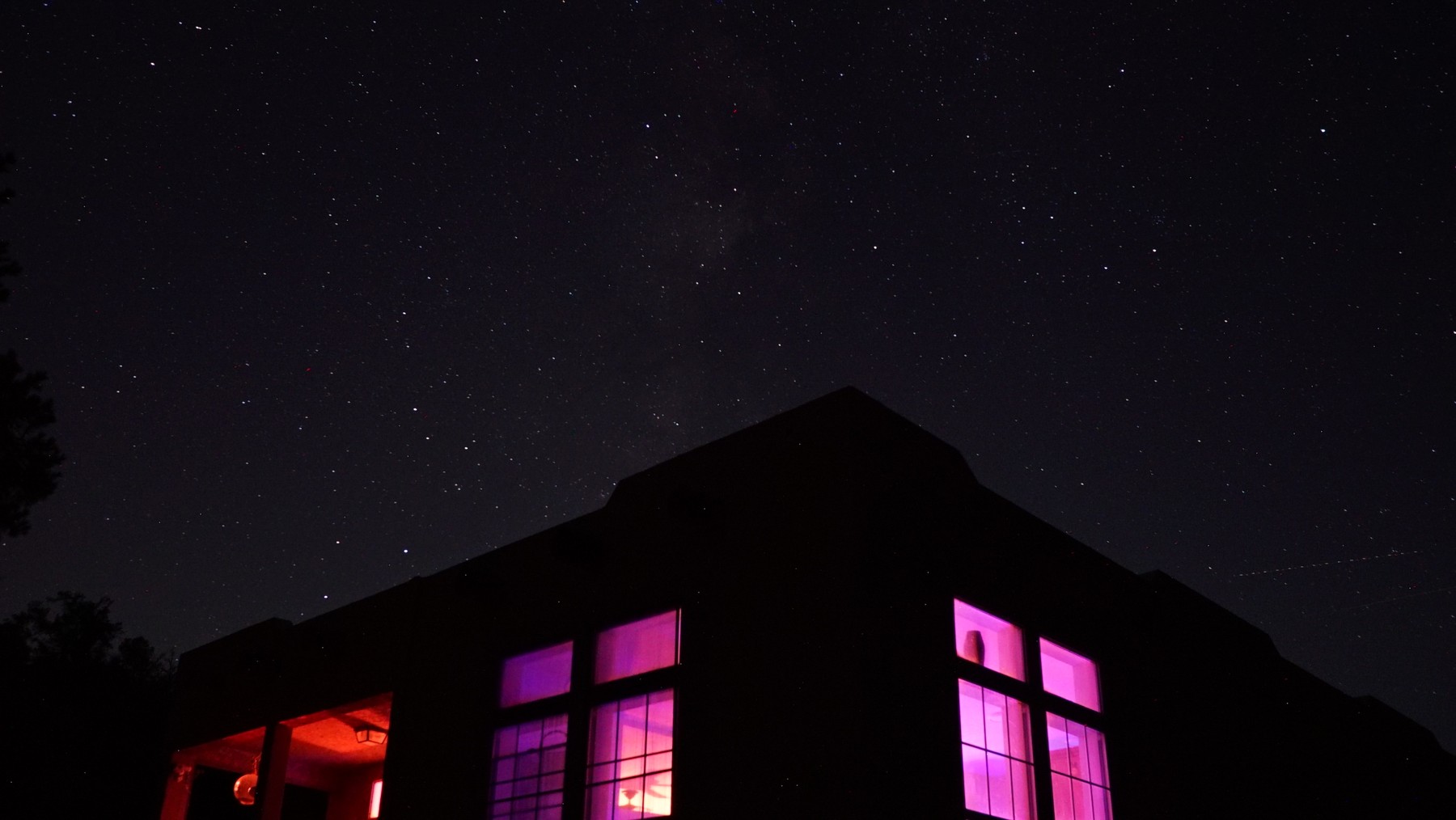 Stars above the ranch house and its glowing windows at night